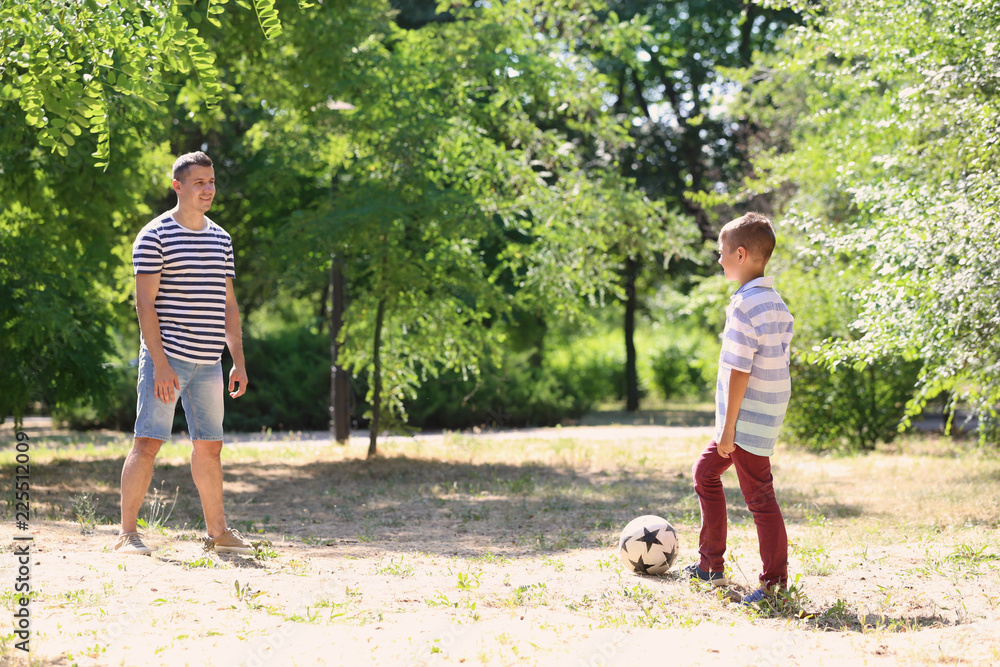 Little boy with his dad playing football outdoors