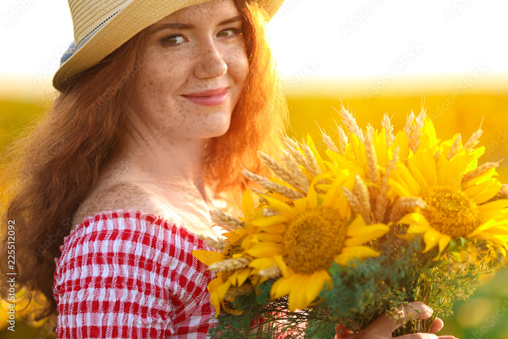 Beautiful redhead woman in sunflower field on sunny day