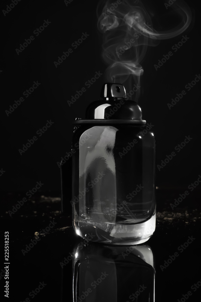 Bottle with perfume and fume on black background