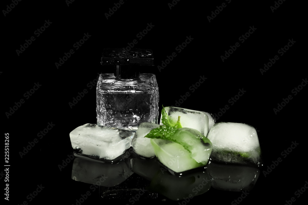 Bottle of perfume, ice cubes and mint on black background