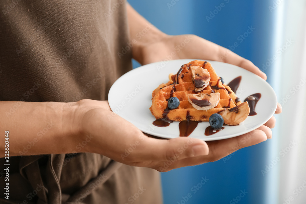 拿着美味华夫饼和浆果的盘子的女人，特写