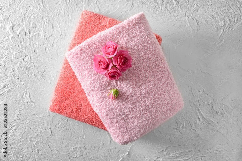 Stack of clean soft towels with flowers on white table