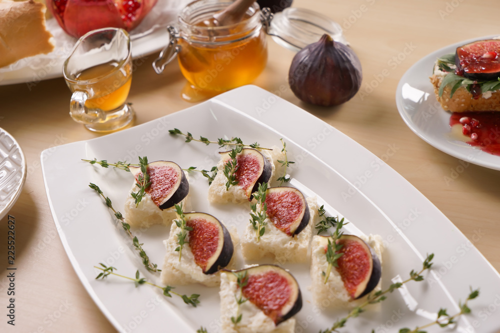 Tasty canapes with ripe fig and cream cheese on plate