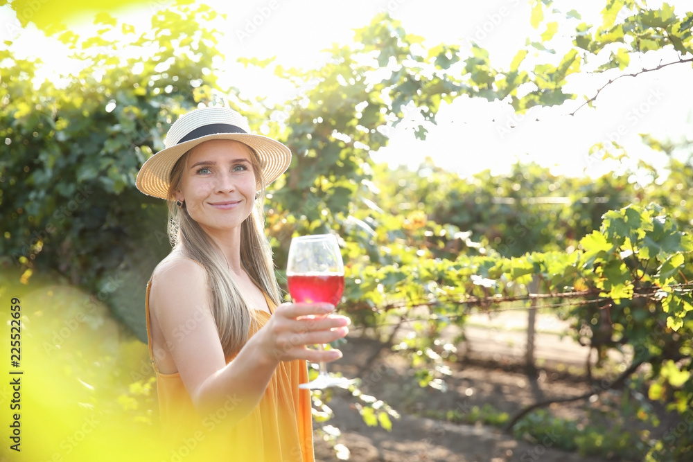 Young woman with glass of red wine in vineyard