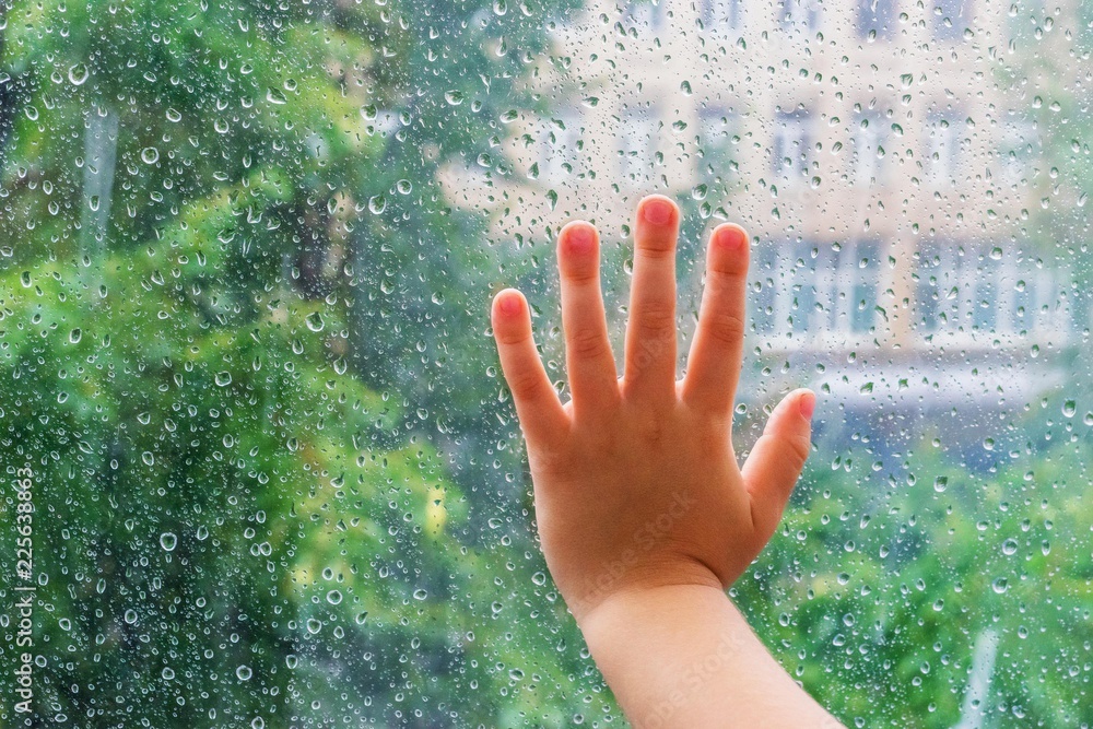 Childrens hand on wet glass with drops