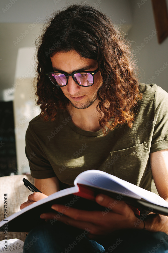 Close up of a male student writing notes in a book