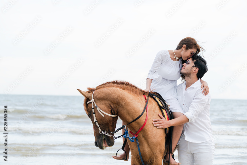 年轻夫妇在热带海滩上骑马。