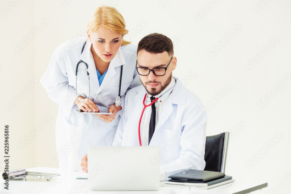 Doctor at hospital works on computer with partner.