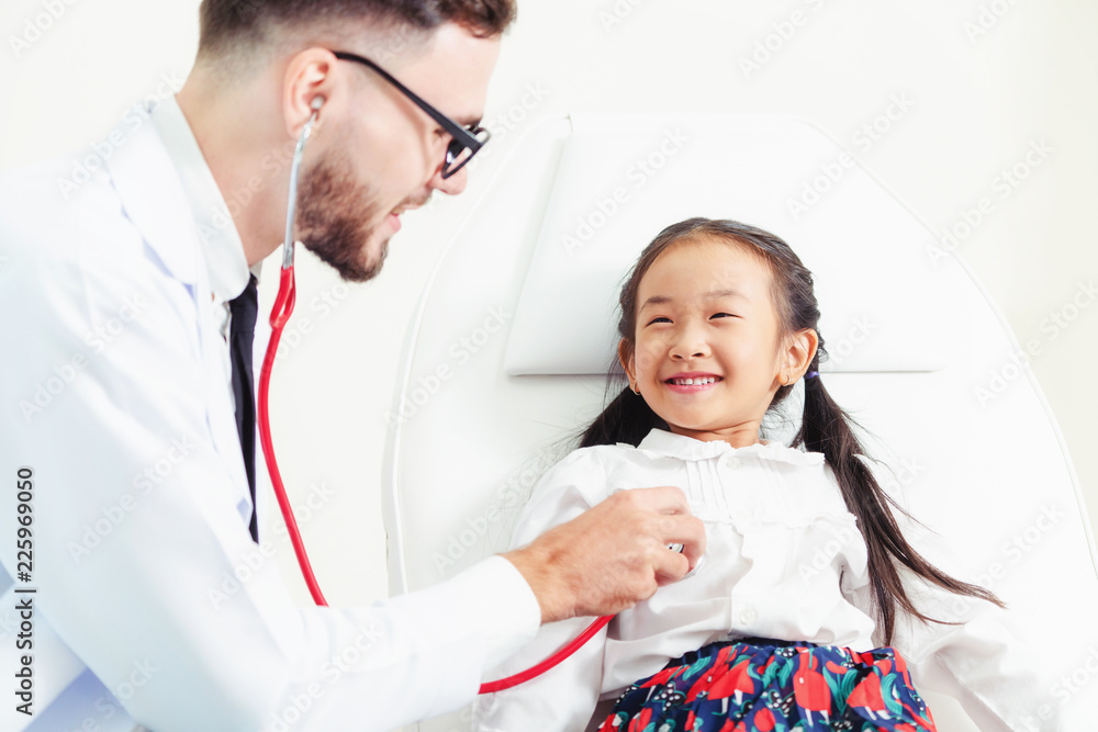 Doctor examining little happy kid in hospital.