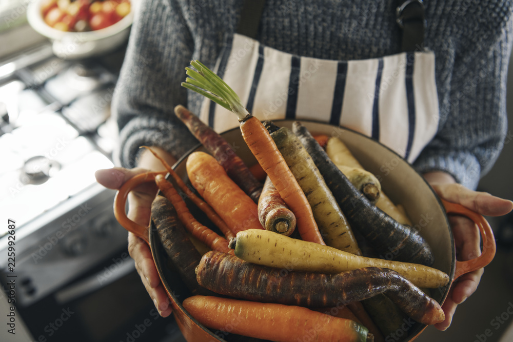 Woman holding a bowl of carrots and turnips