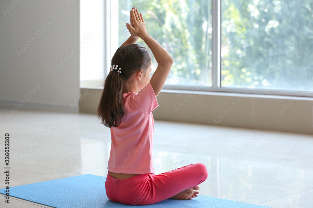 Little girl practicing yoga indoors