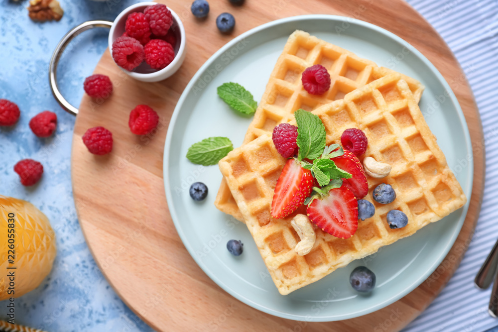 Plate with delicious waffles and berries on table, top view