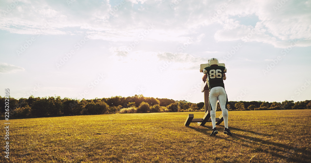 American football player doing tackling drills on a sports field