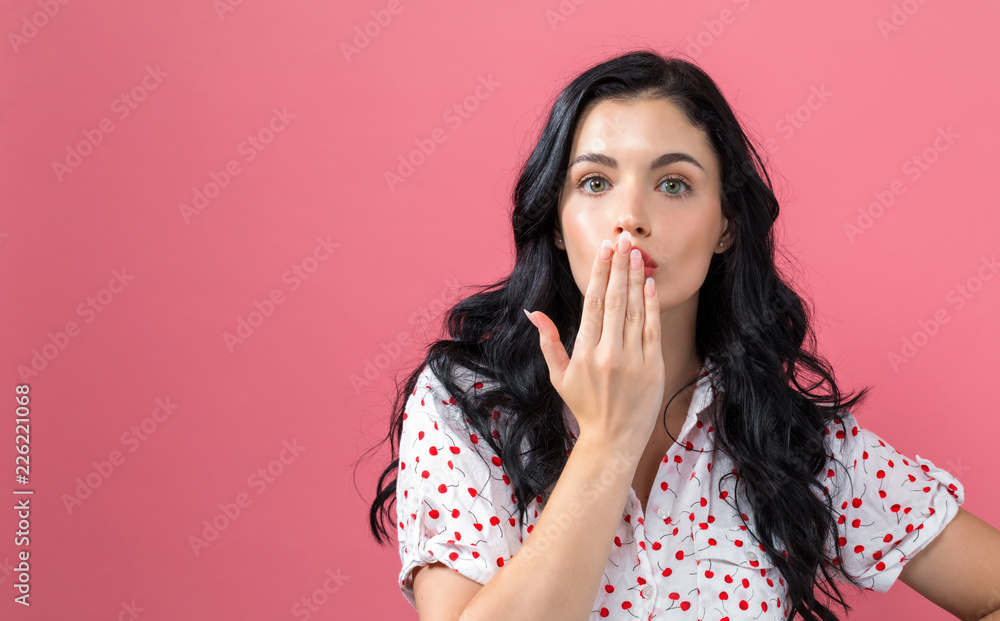 Young woman covering her mouth on a solid background