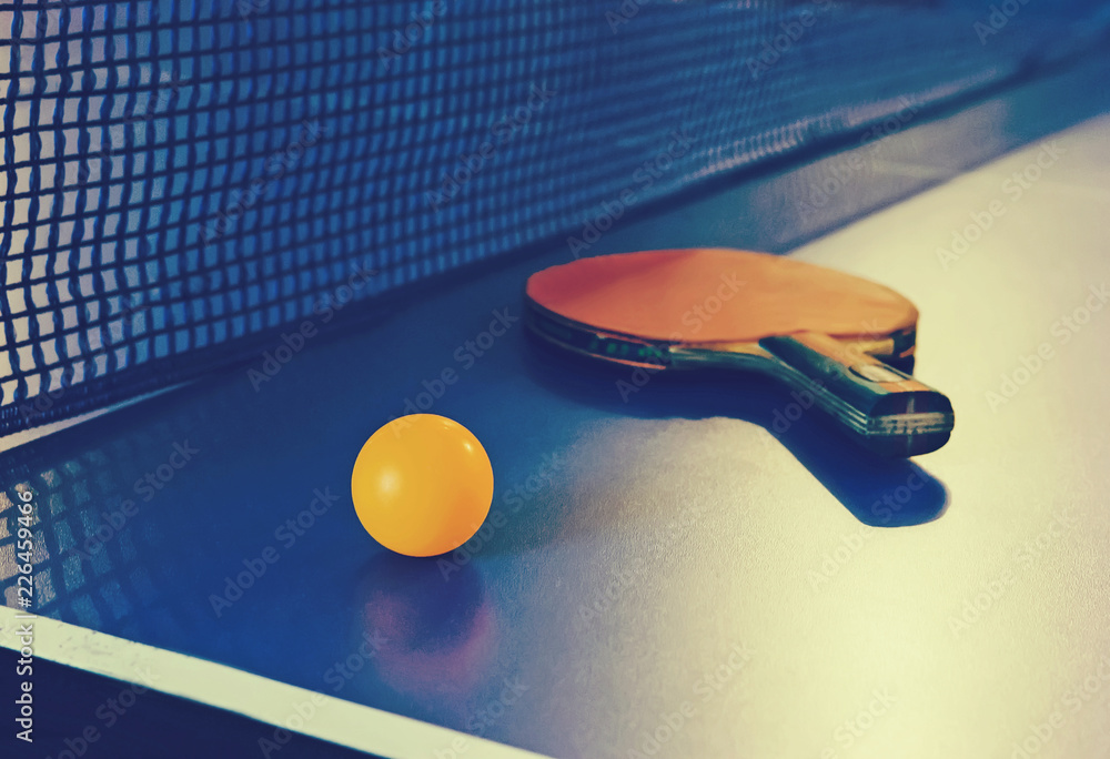 Table tennis racket and ball on blue table