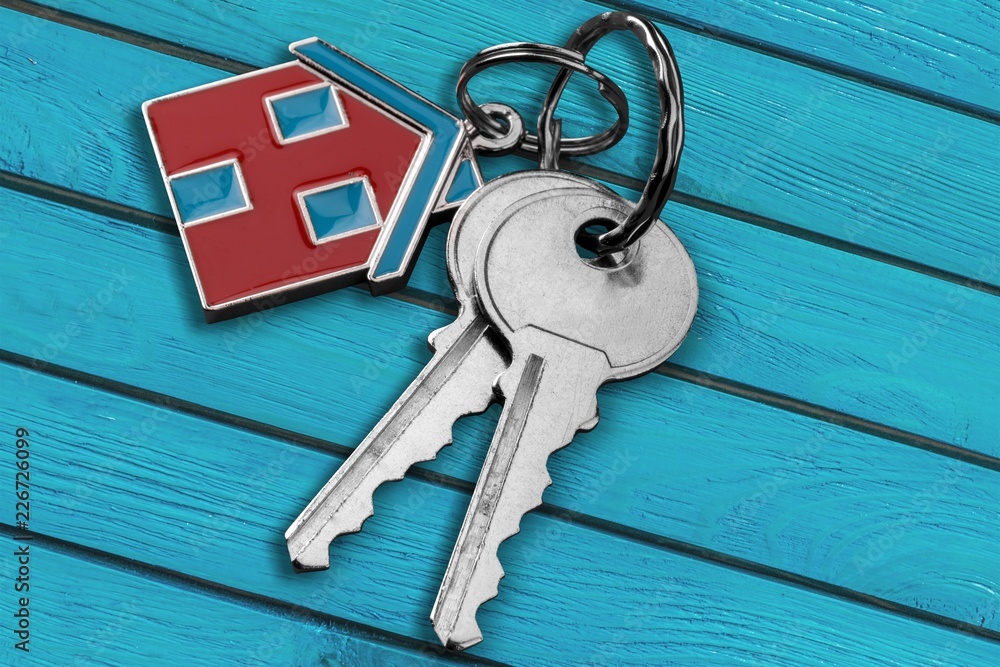 House keys with trinket on wooden desk