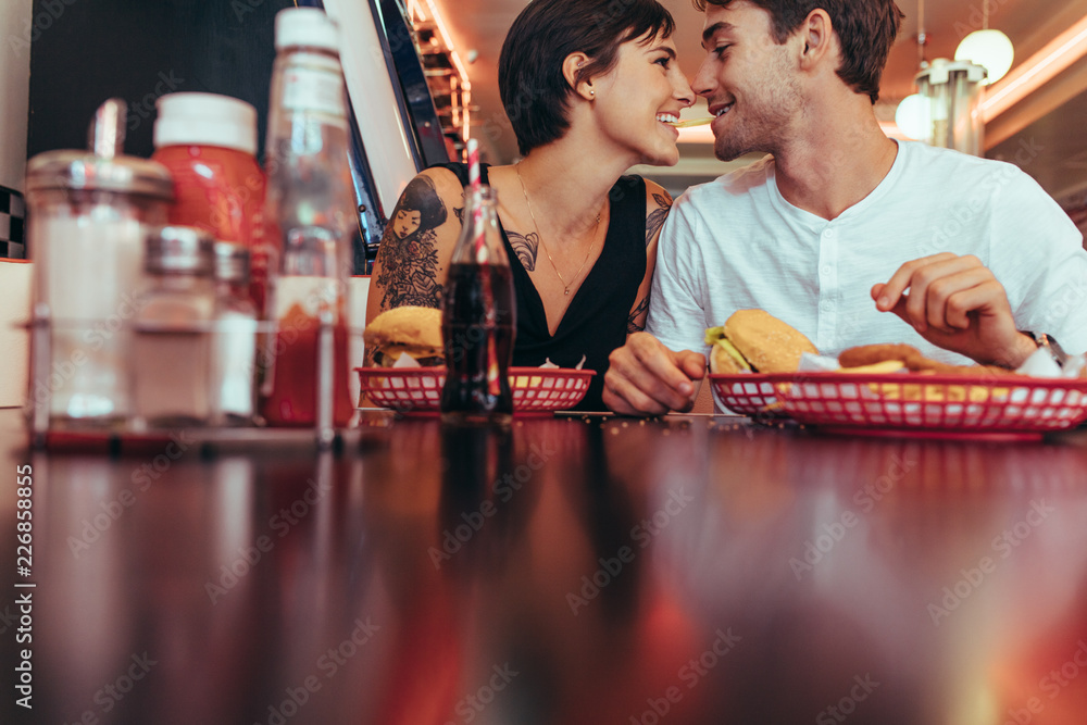 Man and woman sharing a french fry sitting at a restaurant