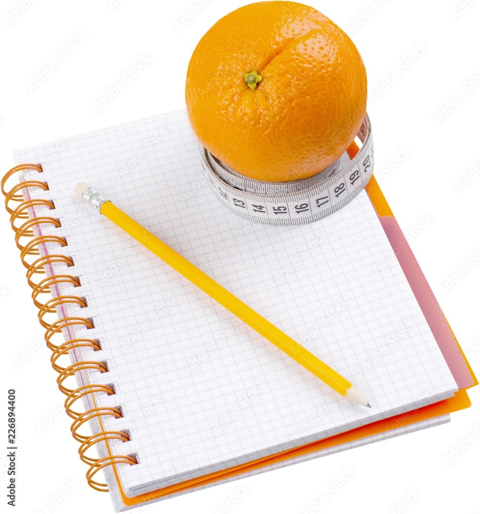 Orange with tape measurer around it on top of a food journal -