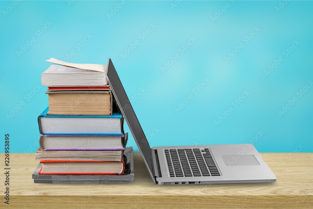 Stack of books with laptop on table