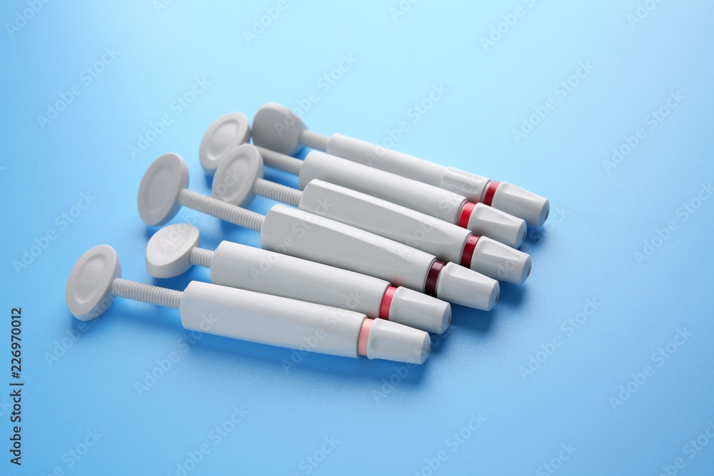 Syringes of resin luting cement on color background