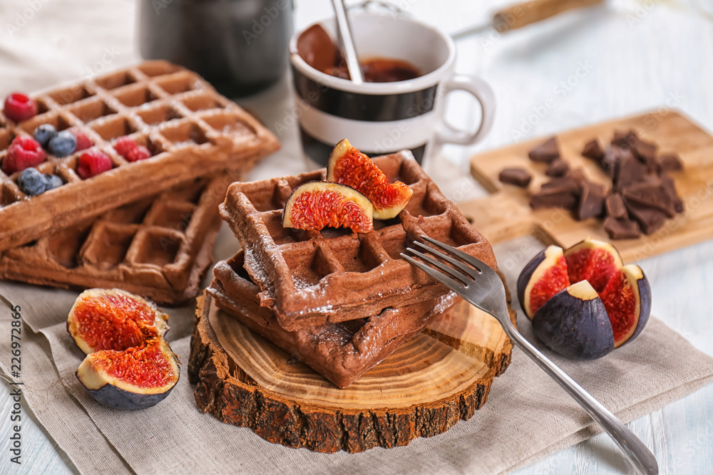 Delicious waffles with fig slices on wooden board