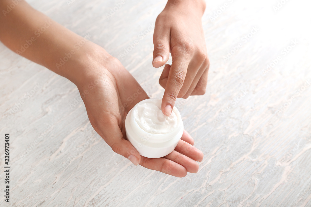 Young woman applying body cream, closeup