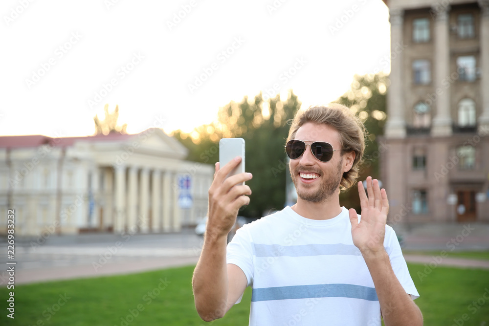 Handsome young man taking selfie in park