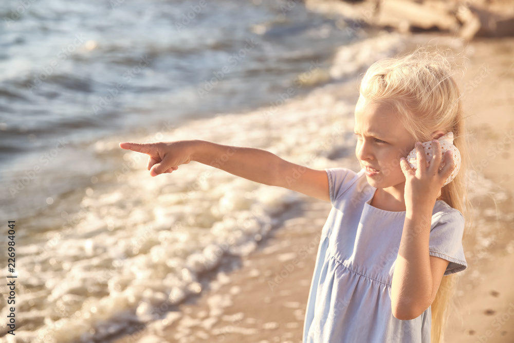 Cute little girl with sea shell on beach