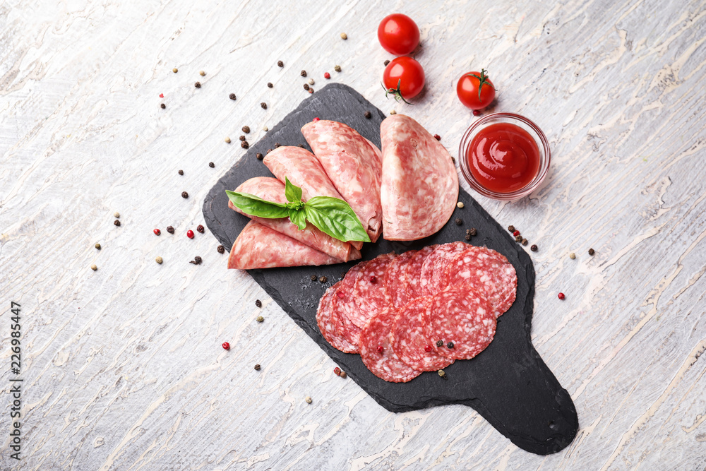 Slate plate with different kinds of sausages and sauce on light table