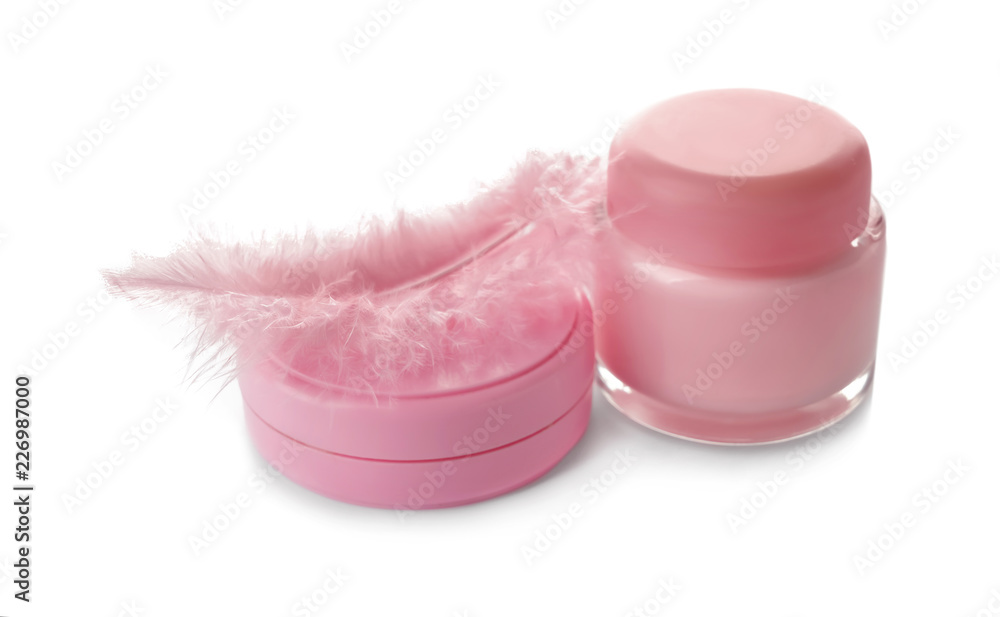 Jars with body cream and pink feather on white background