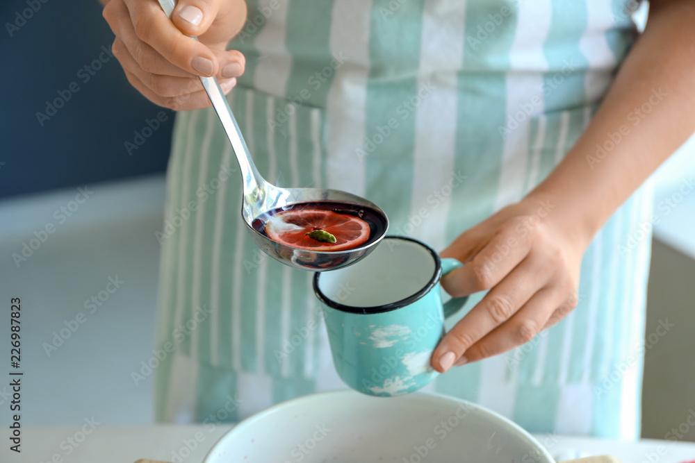 Woman pouring hot mulled wine from ladle into cup