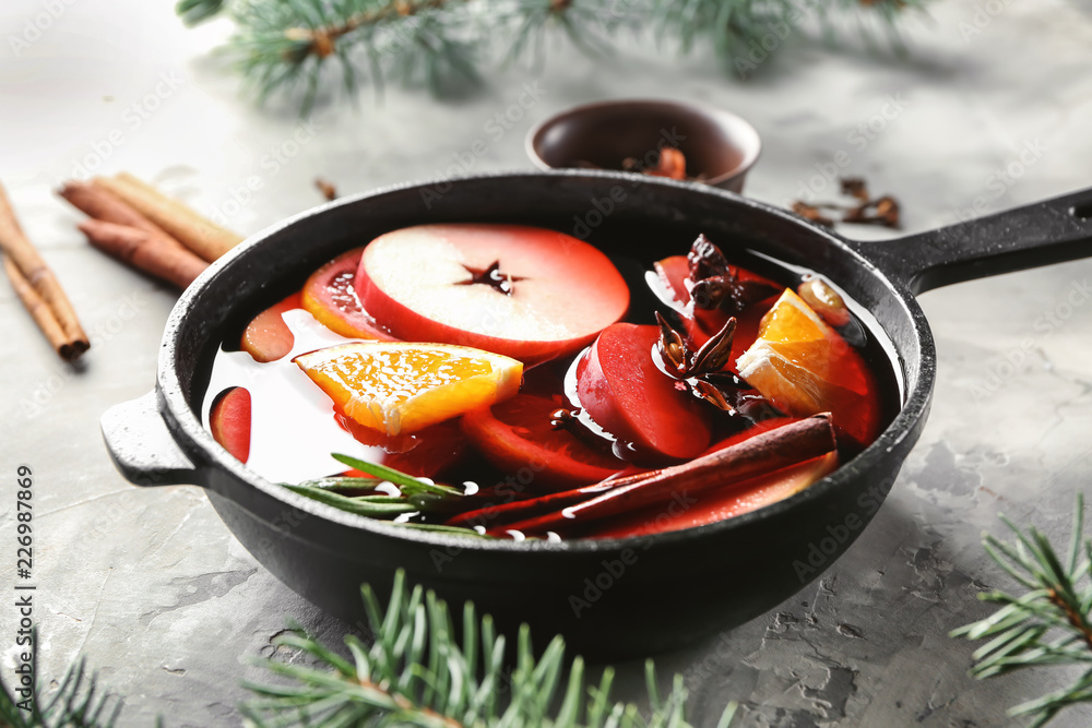 Saucepan of delicious mulled wine on grey table