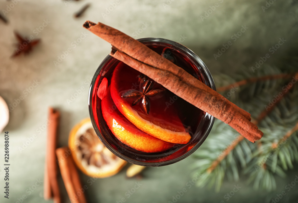 Glass of delicious mulled wine on color table