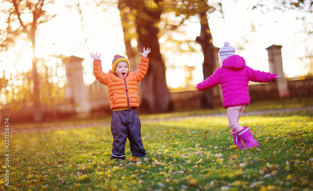 children throwing leaves in beautiful autumnal day