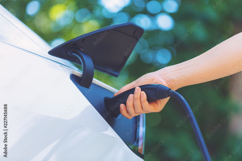 Person charging an electric vehicle with green background