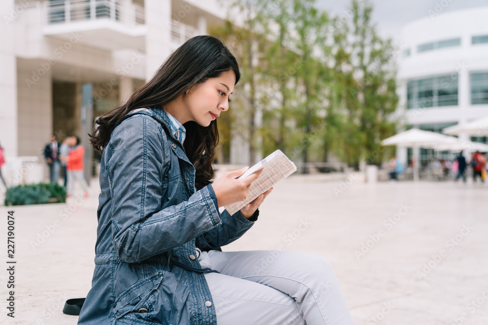 student sitting outdoor reading book