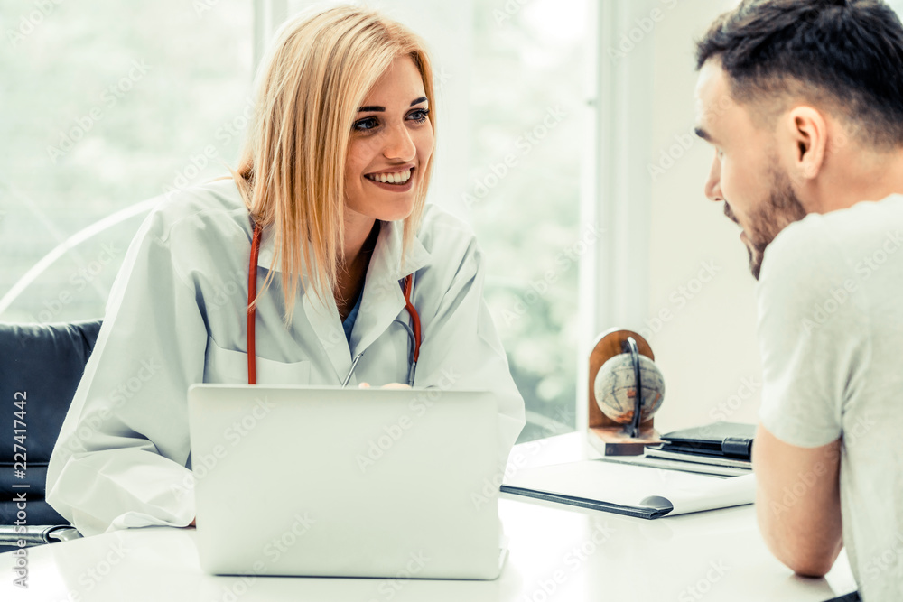 Woman doctor is talking to male patient in hospital office. Healthcare and medical service.