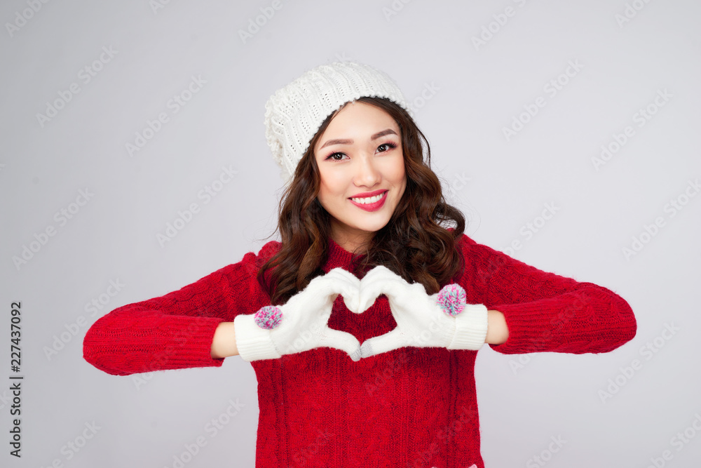 Beautiful smiling woman in warm clothing gesture heart shape