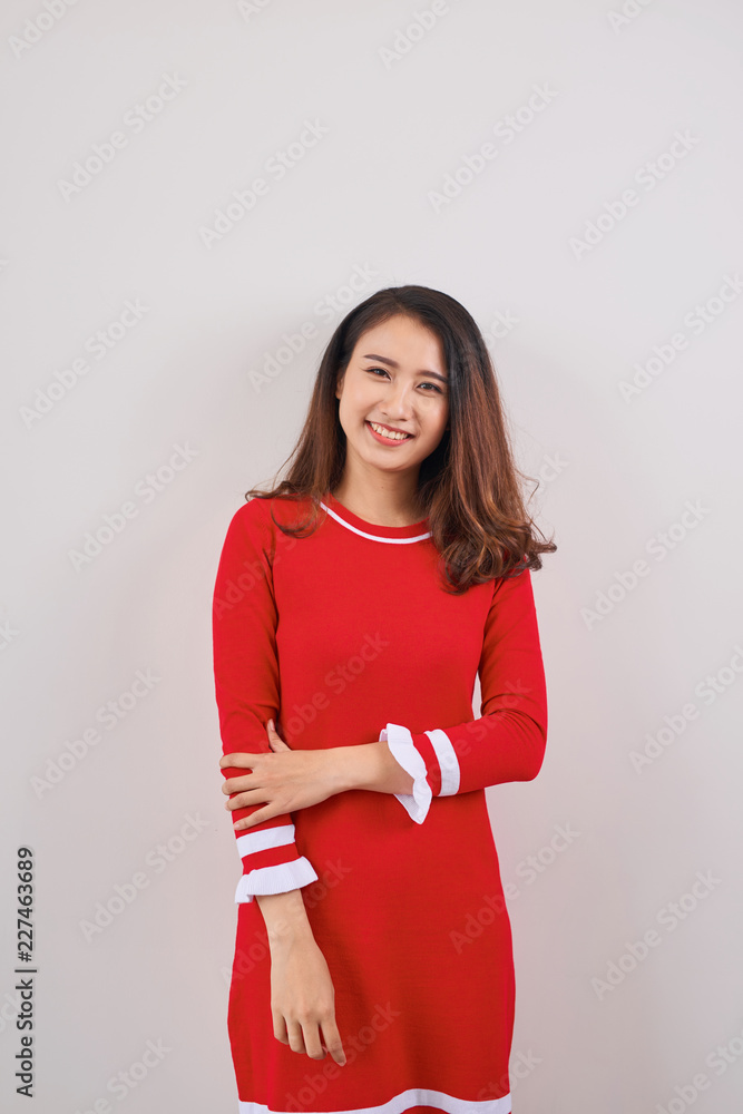 Full length of smiling playful young woman in red dress standing and looking up over white backgroun