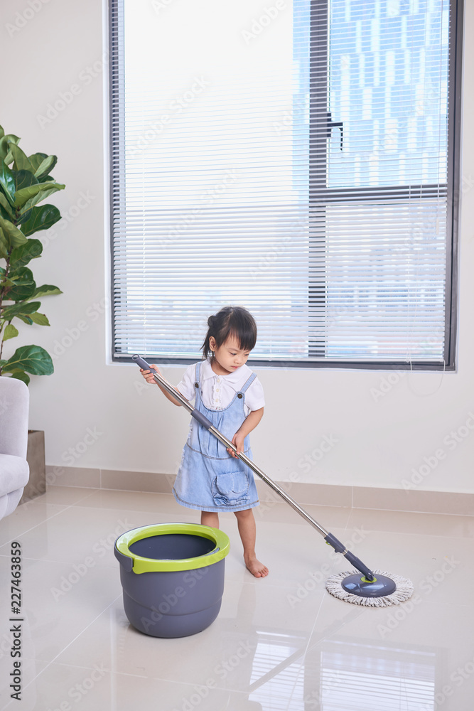 A little cute asian girl doing house cleaning with mop