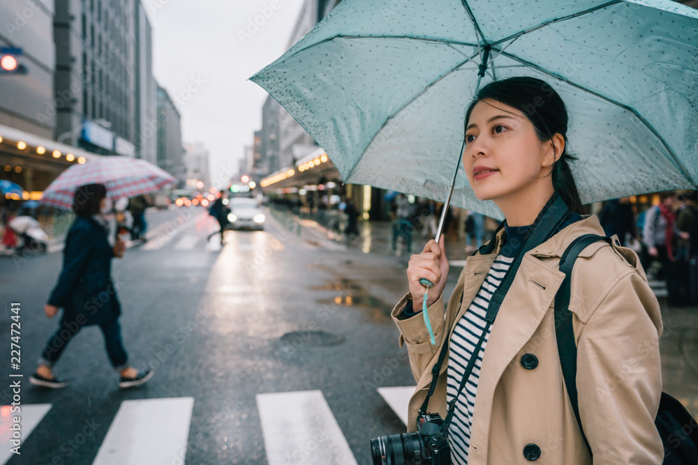 女士撑着蓝色雨伞过马路