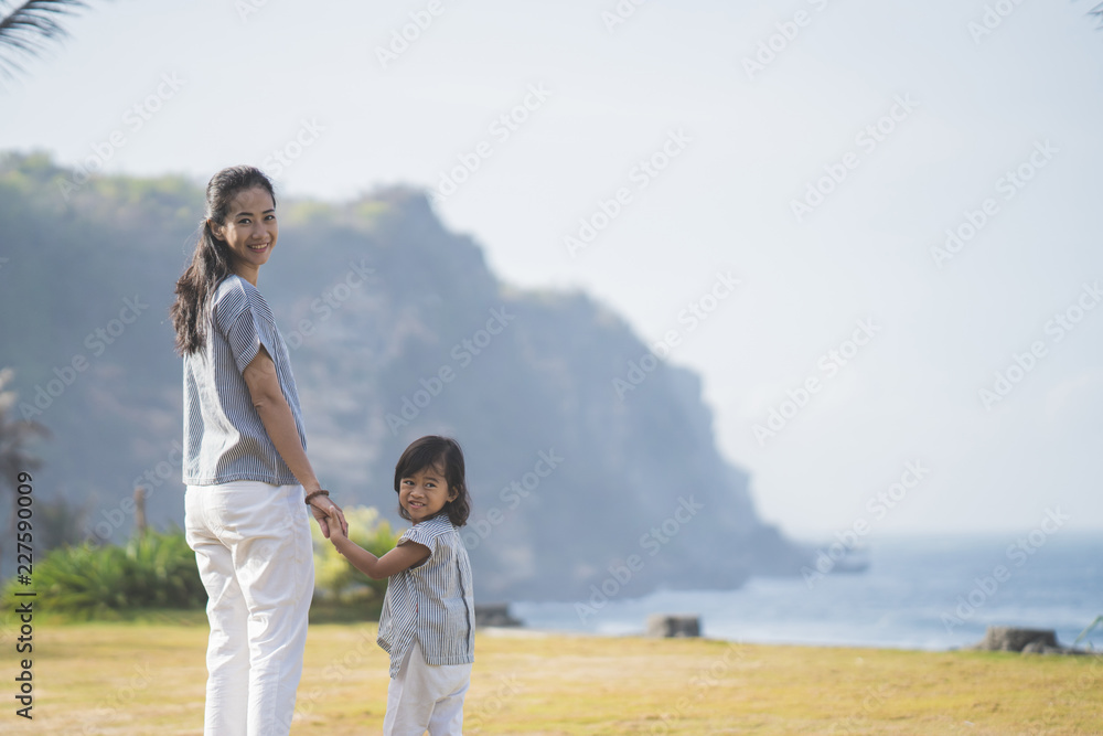 一个女人和他的女儿在公园里走来走去，回头看客串