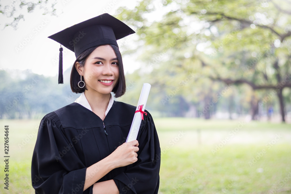 毕业那天，年轻的亚洲女性在大楼外的肖像。亚洲女孩双手握着ce