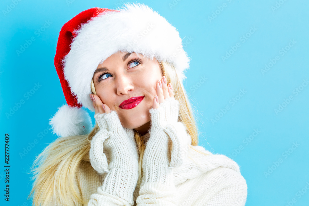 Happy young woman with Santa hat on a blue background