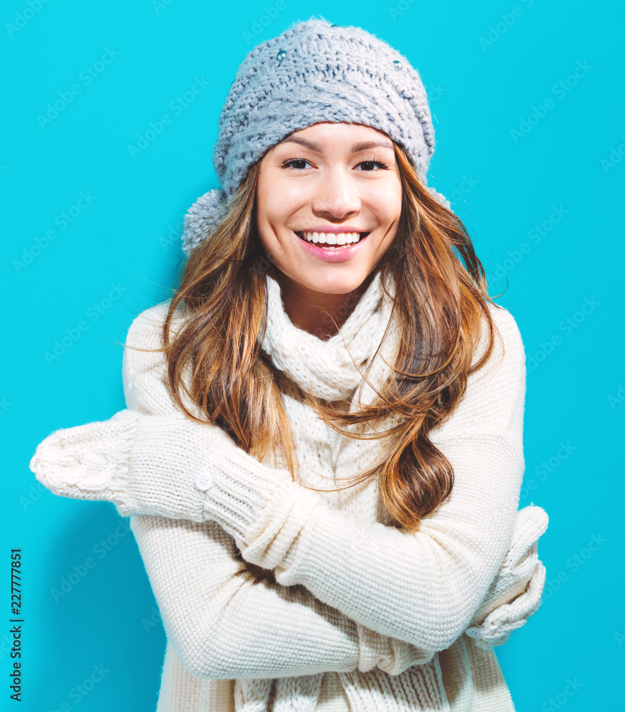 Happy young woman in winter clothes on a blue background