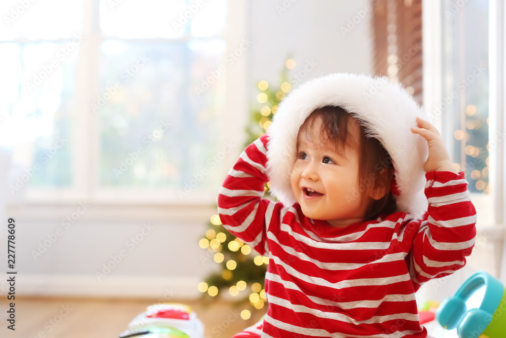 Happy toddler boy with a Santa hat playing on Christmas