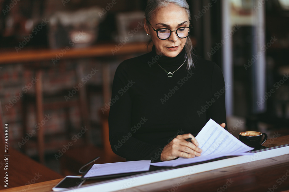 成熟的女商人在咖啡馆读一些文件