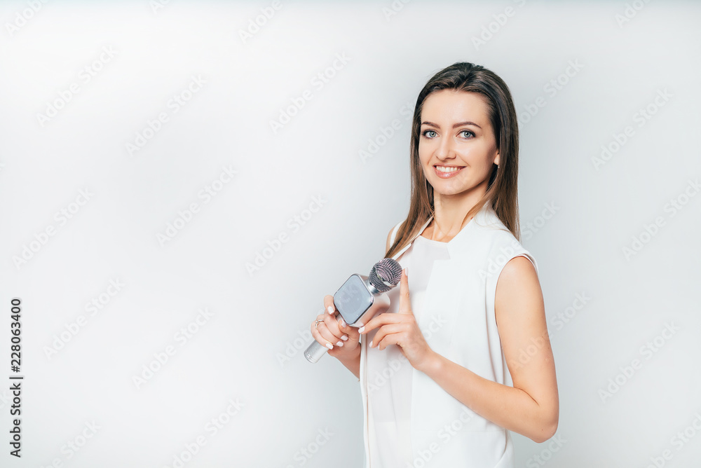 beautiful journalist smiles and holds in her hand a microphone in the studio on a white background. 