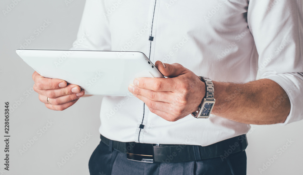 modern white tablet is in the hands of a businessman in the office on the white background. Close-up