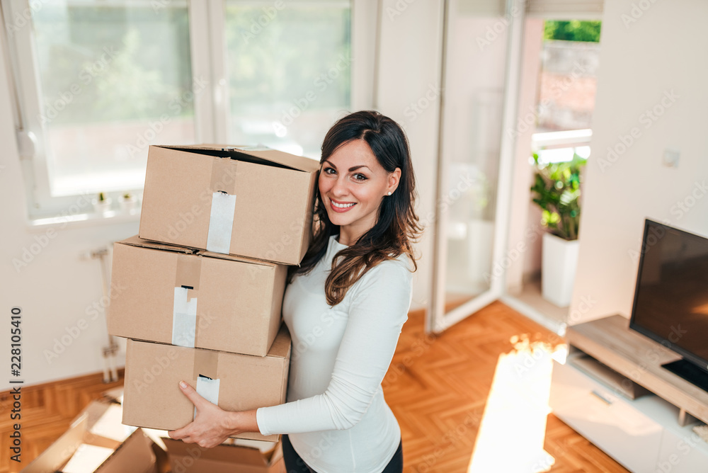 Smiling young woman moving to a new apartment.